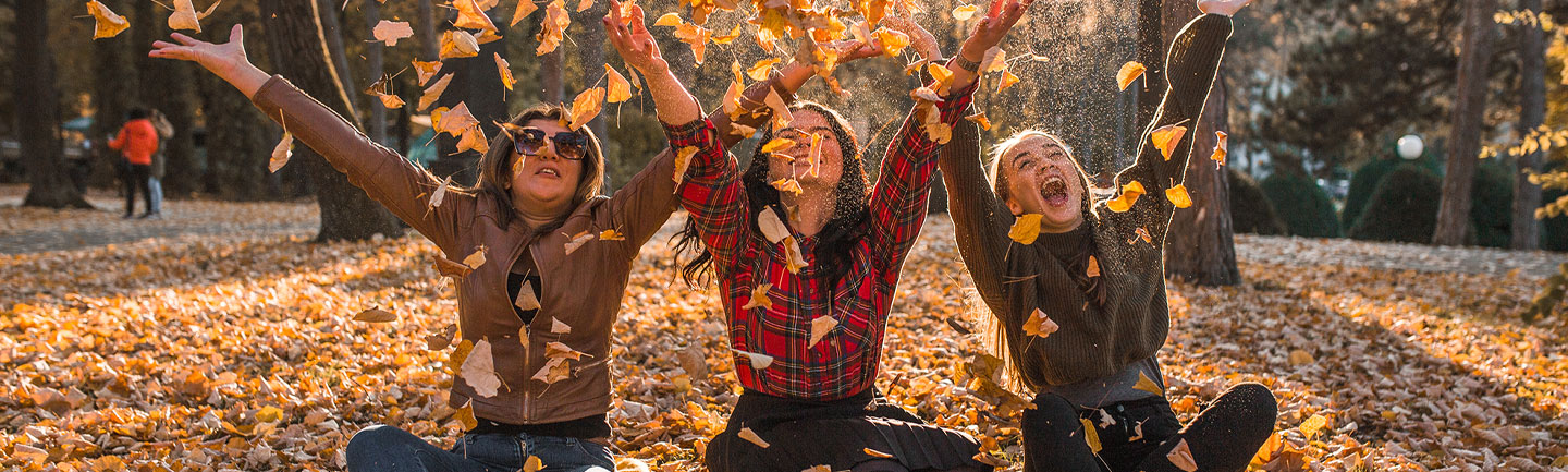Three women throwing leaves into the air