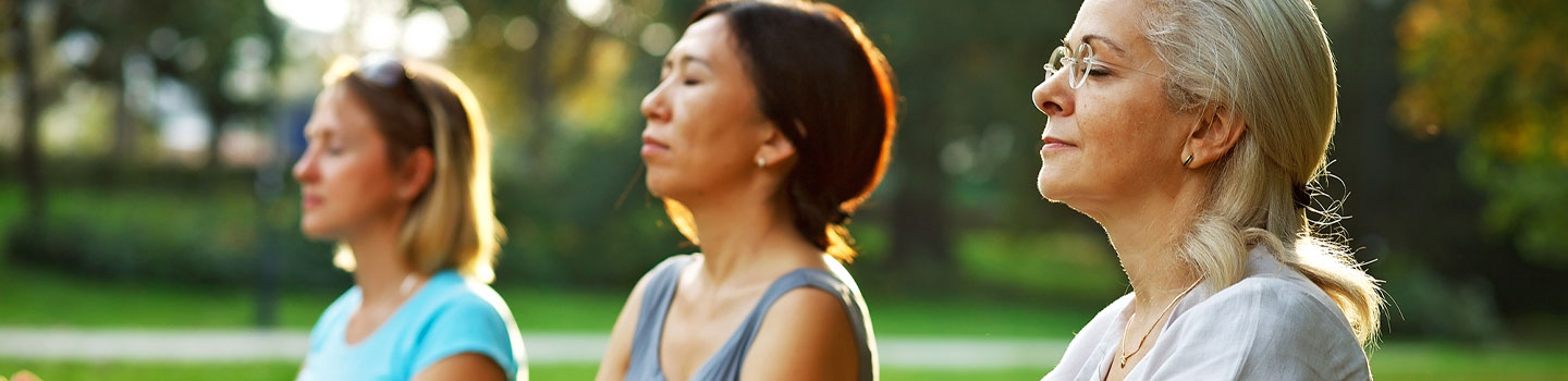 Three women meditating outside