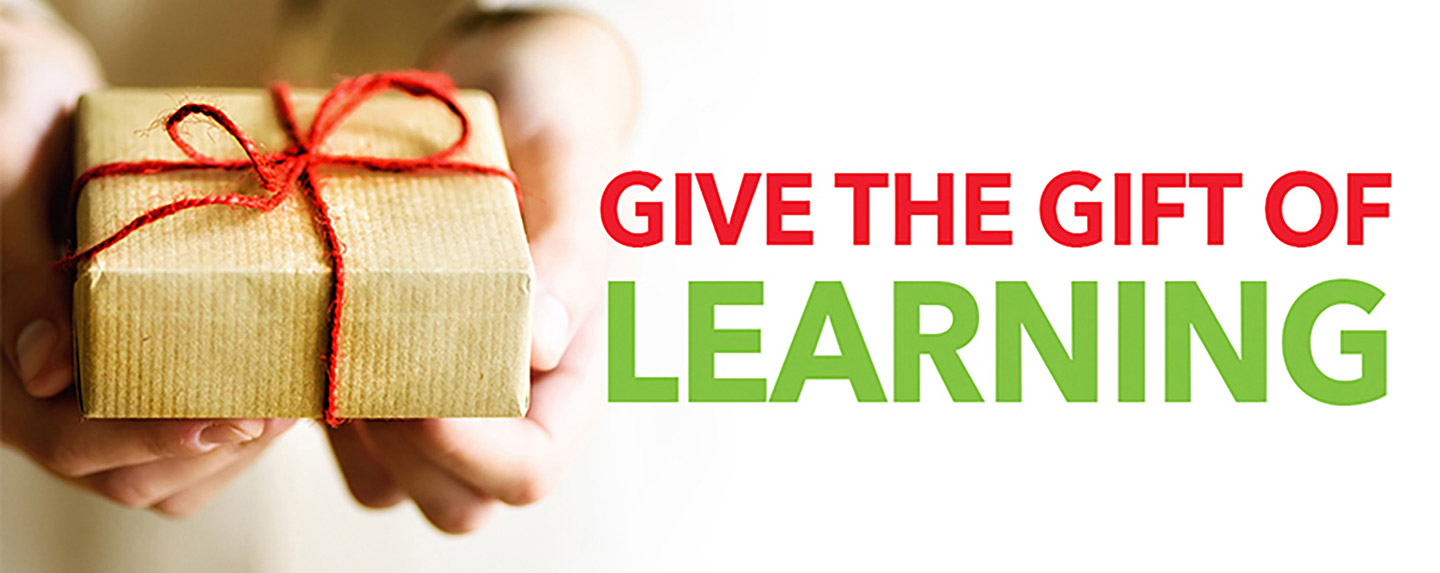 Photograph of a person holding a wrapped gift with the words "Give the Gift of Learning" written beside it.