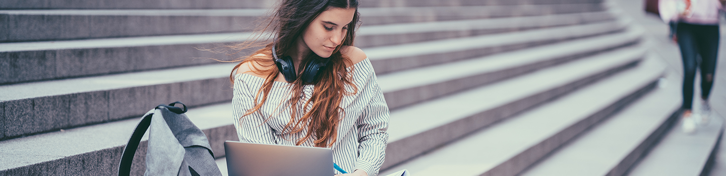 Student sitting on steps working on a laptop