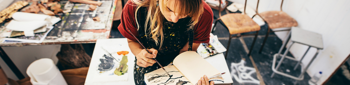 Woman painting in a journal