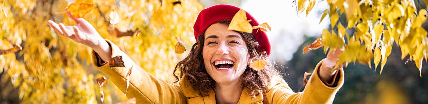 Woman in a fall jacket playing with colourful fall leaves