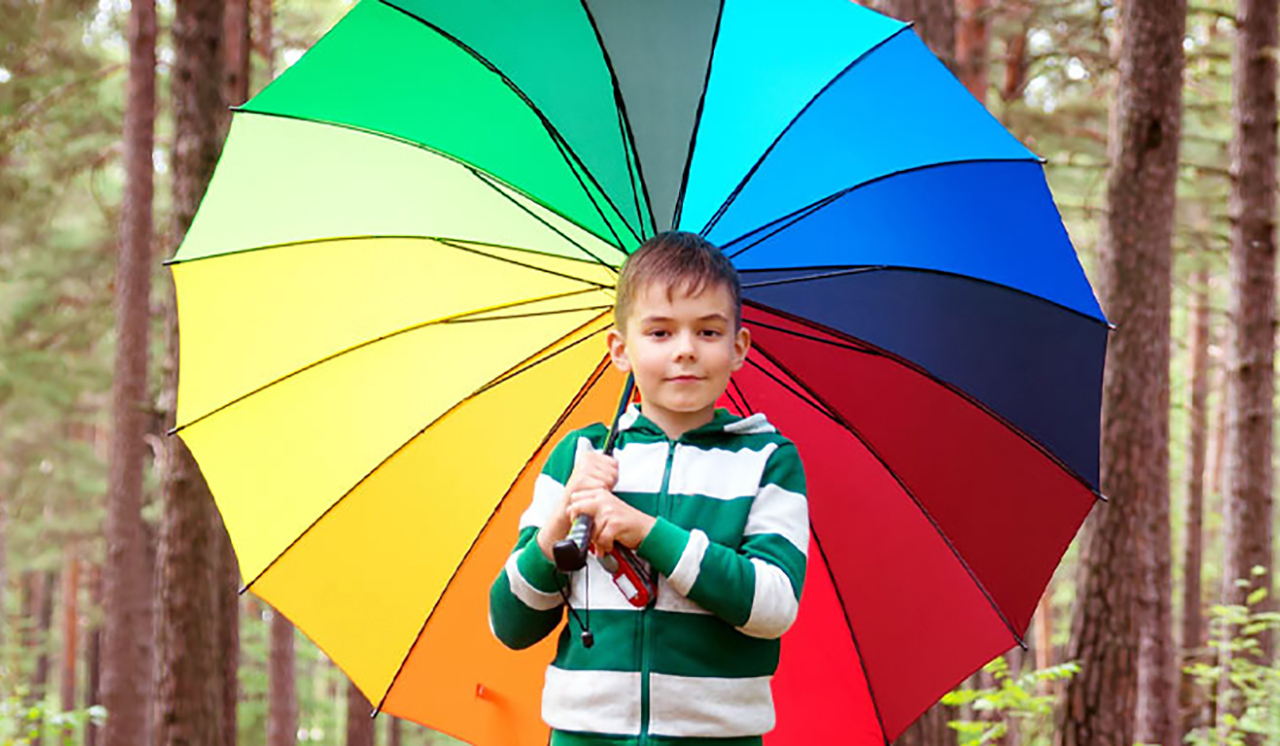 Boy holding a rainbow-coloured umbrella