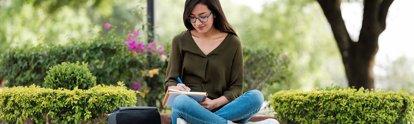 Student sitting outside with a notebook