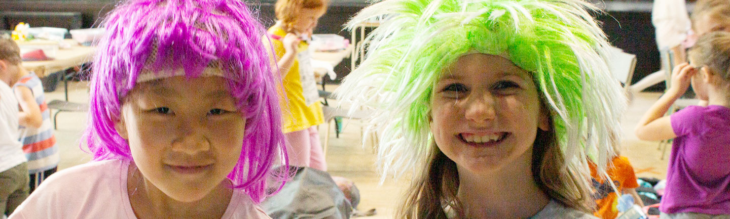 Photo of 2 children wearing brightly coloured wigs