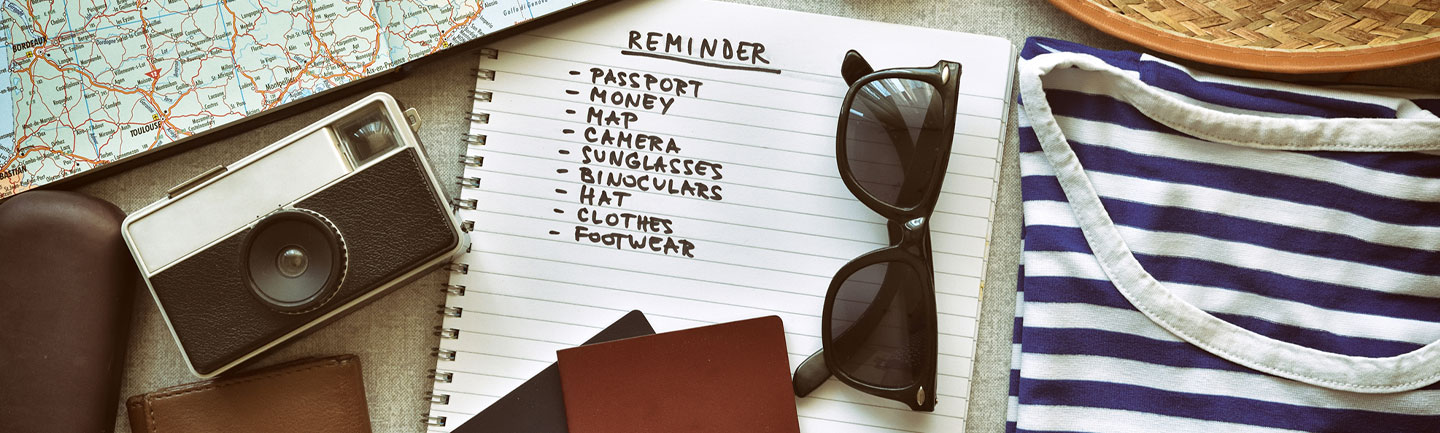 Photo of travel items including sunglasses, a camera, an itinerary, and more