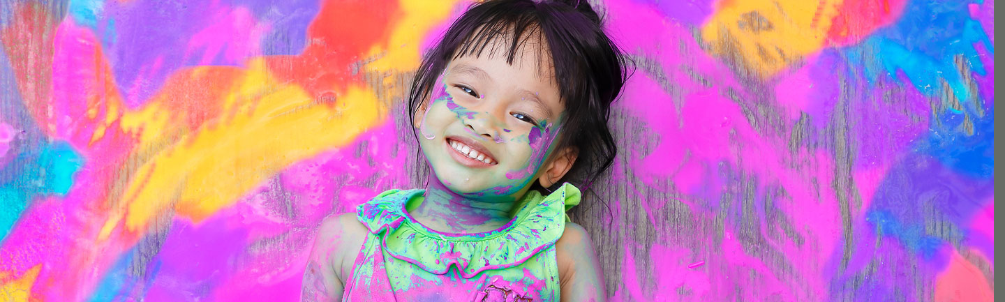 Colourful image of a child with paint on her