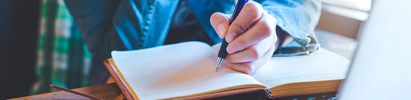This is a photo of a person's hand holding a pen writing in a journal.