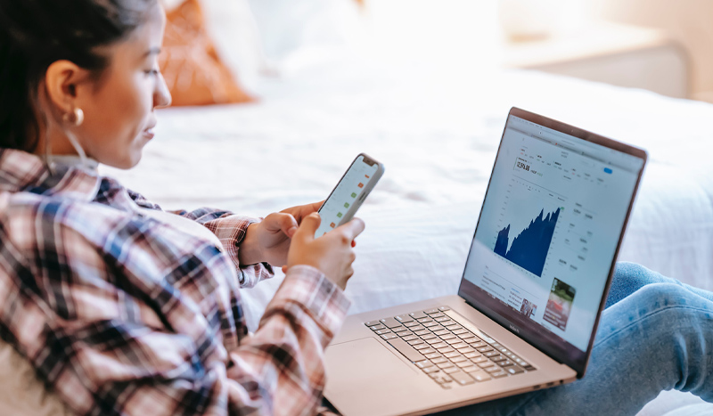 Individual looking at data on a laptop and cell phone