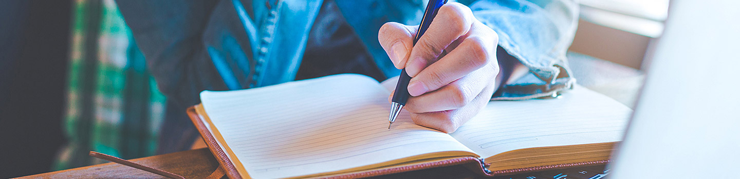 Photograph of a person writing in a notebook