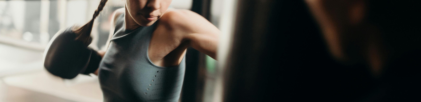 Young woman in boxing gloves hitting a punching bag