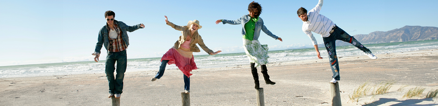 A group of people balancing on posts on the beach