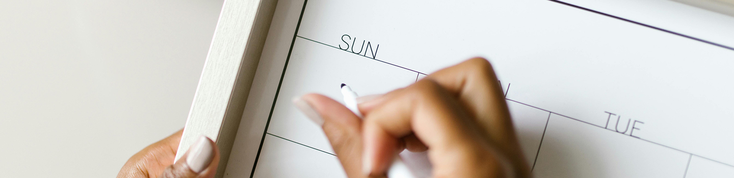 Person starting to fill out a whiteboard dry erase calendar