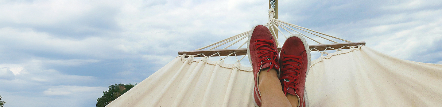 Photograph of someone lying in a hammock with red sneakers