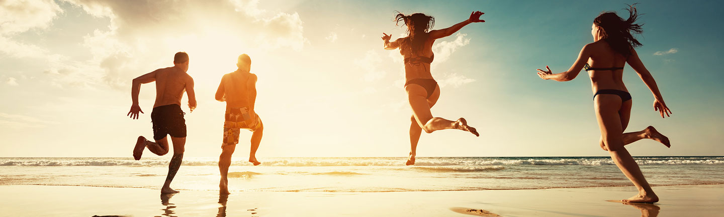 Photo of four people running on a beach