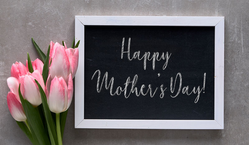 Photo of a sign that says "Happy Mother's Day" with flowers next to it