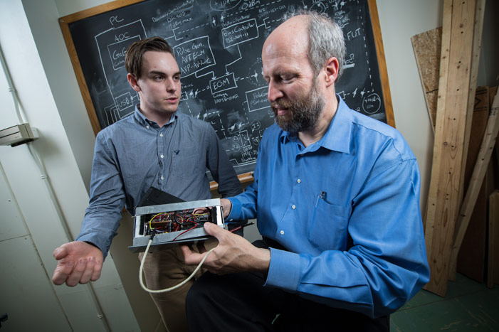 Electrical engineering student Atlin Anderson and Associate Professor Dr. Brent Petersen examine a prototype cube satellite, also known as a CubeSat.
