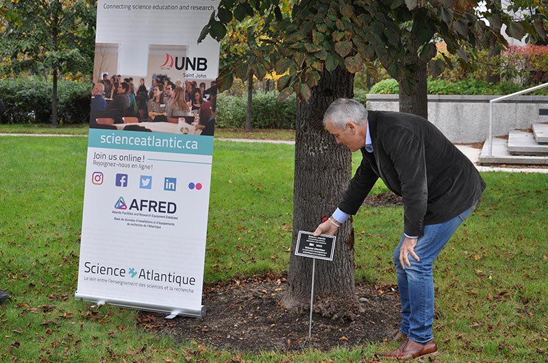 Dr. Michael Van Zyll de Jong, dean of the faculty of science, applied science and engineering at UNB, planting a sign marking Science Atlantic’s 60th anniversary. Credit: Laura Devlin.