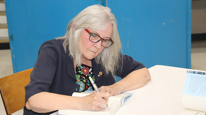 Photo of Dr. Marie Wilson signing copies of her book, North of Nowhere: Song of a Truth and Reconciliation Commissioner.