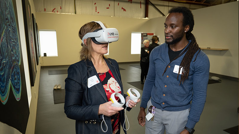 Dr. Petra Hauf, UNB provost and vice president academic, tries a virtual reality headset assisted by Ollando Brown, education technology specialist.