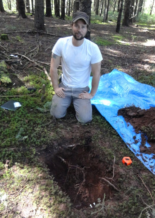 Dr. Anthony Taylor is shown in the field, with an excavated test pit from which soil samples are taken.